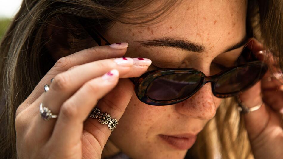 Eine Frau mit Sommersprossen und Sonnenbrille