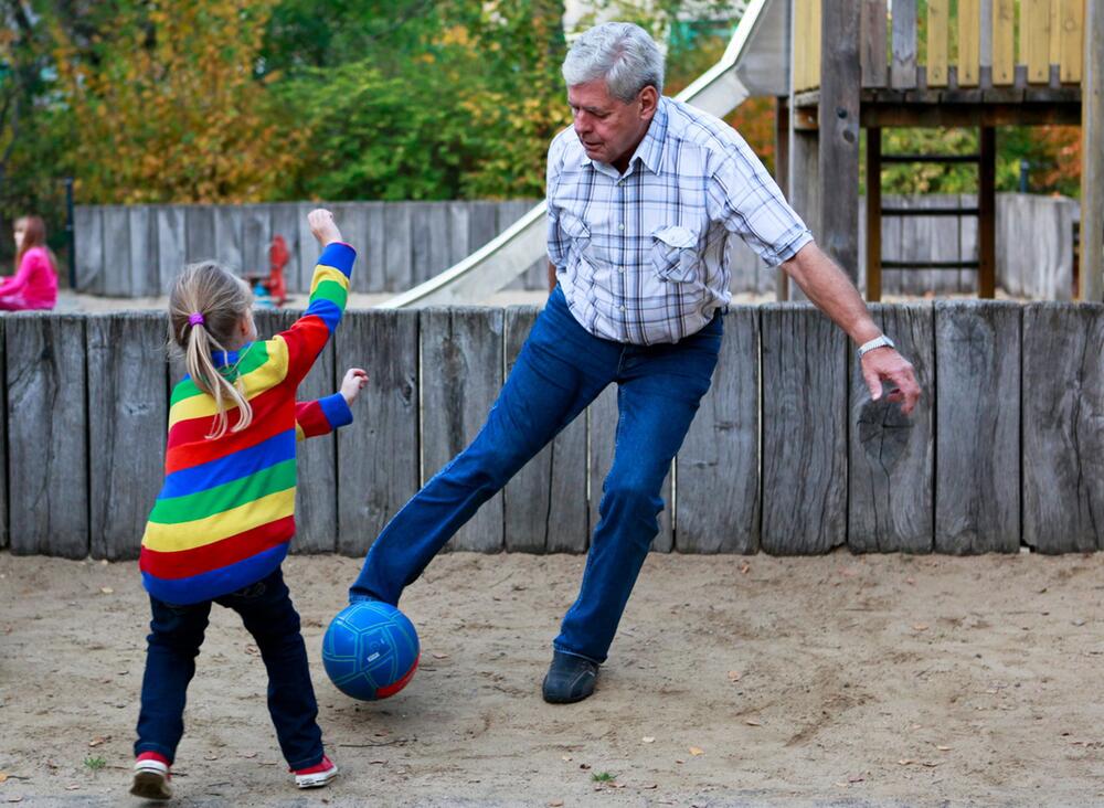 Ein Grossvater spielt mit seinem Enkelkind Ball