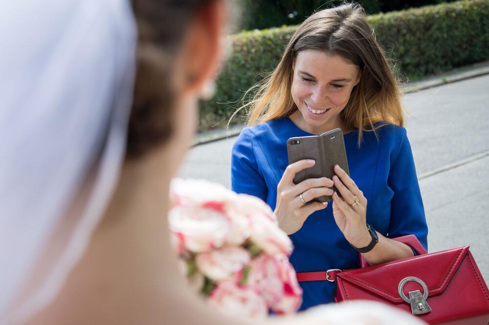 Frau fotografiert die Braut mit einem Smartphone