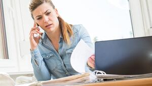 Eine Frau mit Smartphone und Laptop sichtet Unterlagen
