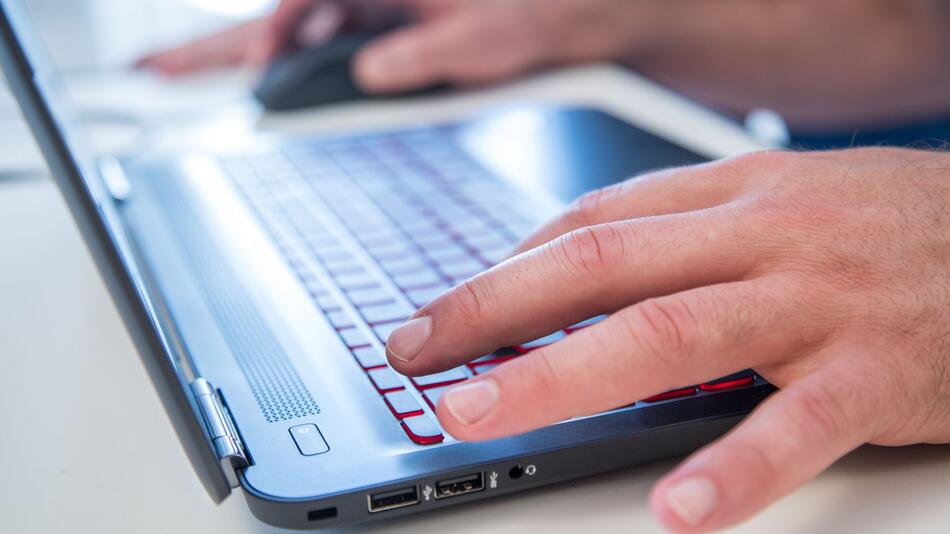 Mann schreibt an einem Laptop