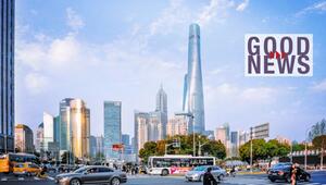Strassenkreuzung in Shanghai mit Hochhäuser-Skyline im Hintergrund, rechts oben der Schriftzug ...