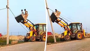 Männer nähern sich in Baggerschaufel einem Strommast – dann gibt der Fahrer Gas