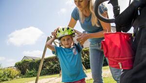 Eine Frau setzt ihrem Kind einen Fahrradhelm auf