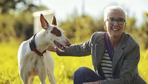 Eine Frau ist in der Hocke und streichelt einen weissen Hund mit braunem Fleck ums Auge.