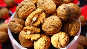 Eine weisse Schale gefüllt mit ganzen Walnüssen in der Schale und zwei aufgebrochenen ...