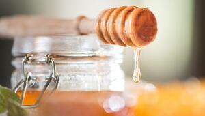 Honig tropft von einem Honiglöffel aus Holz