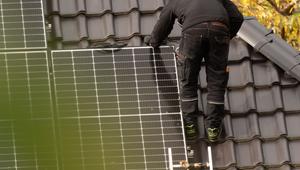 Handwerker arbeitet an Solaranlage auf einem Dach