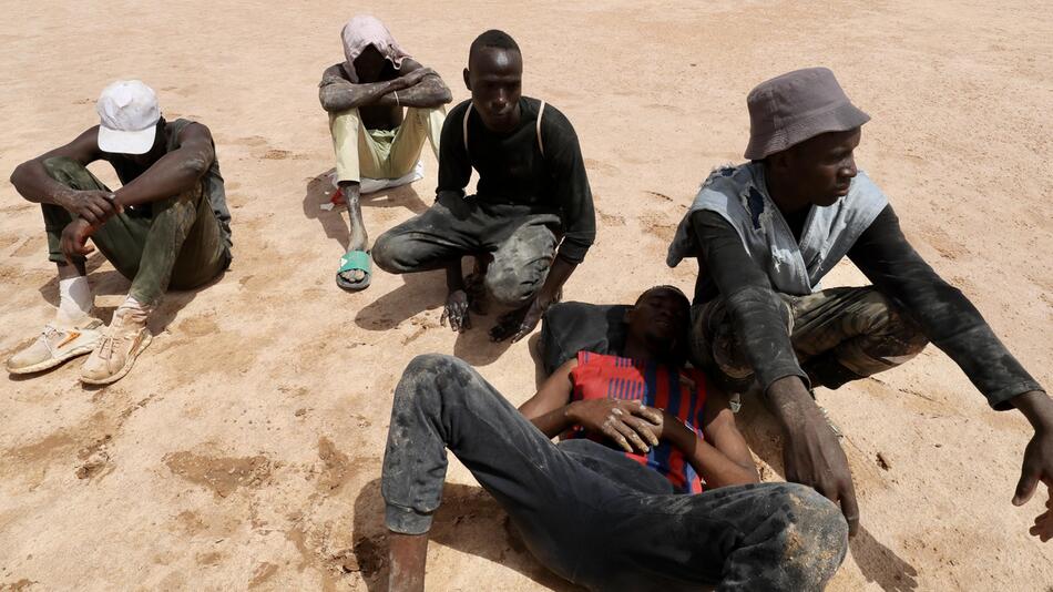 Migranten sitzen in der tunesische Wüste