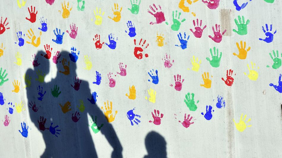 Schatten auf einer Wand mit bunten Handabdrücken