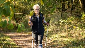 Eine Frau wandert mit Wanderstöcken durch den Wald