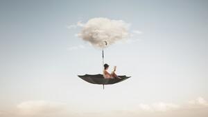 Frau sitzt in Schirm unter einer Wolke im Himmel