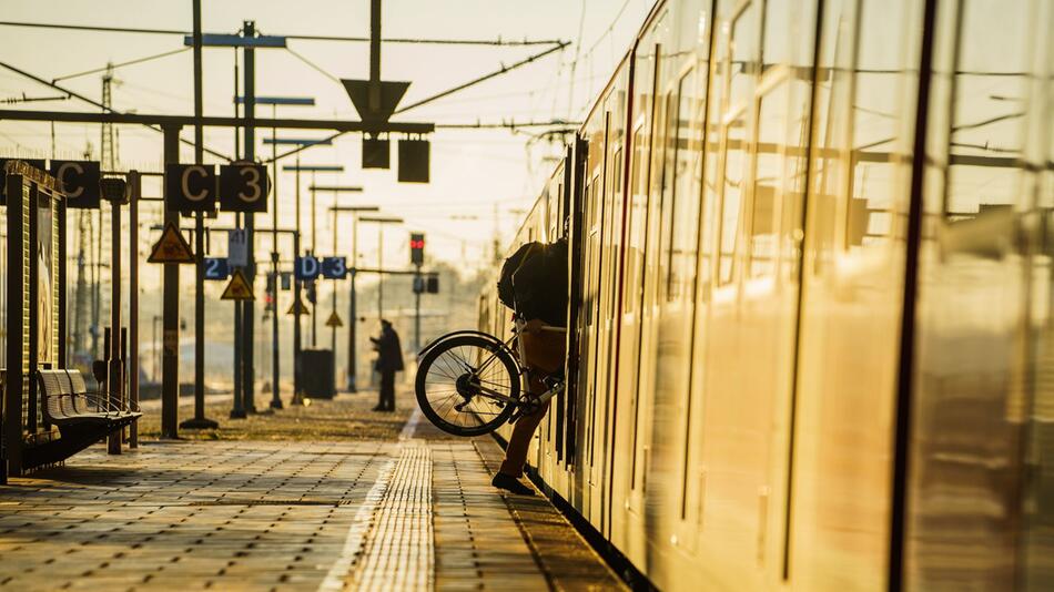 Ein Bahnreisender hebt sein Fahrrad in eine S-Bahn
