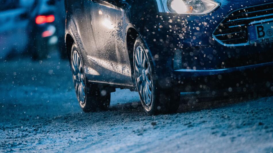 Ein Auto fährt zur dunklen Jahreszeit auf der Strasse