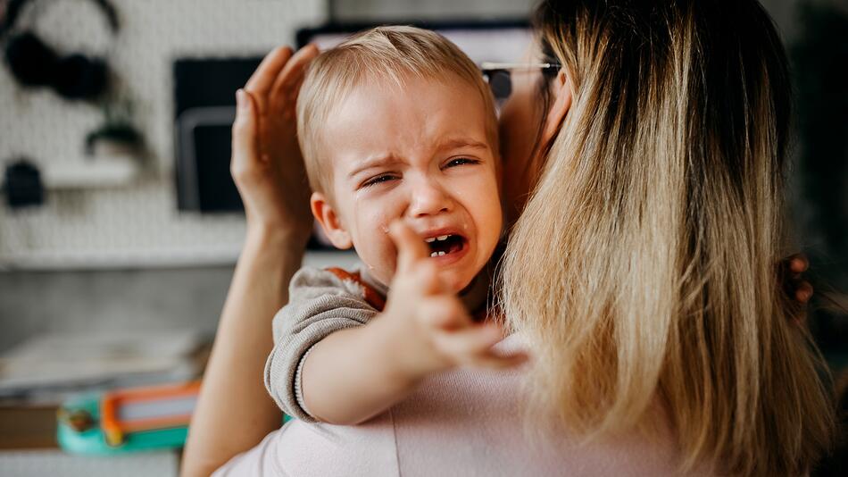 Kleiner Junge weint in den Armen seiner Mutter