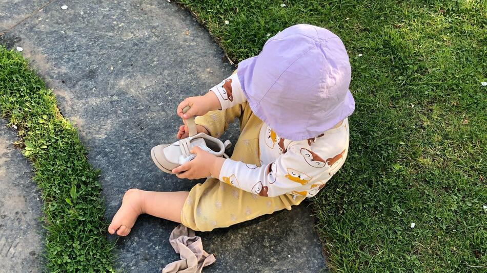Kleinkind zieht sich einen Schuh an