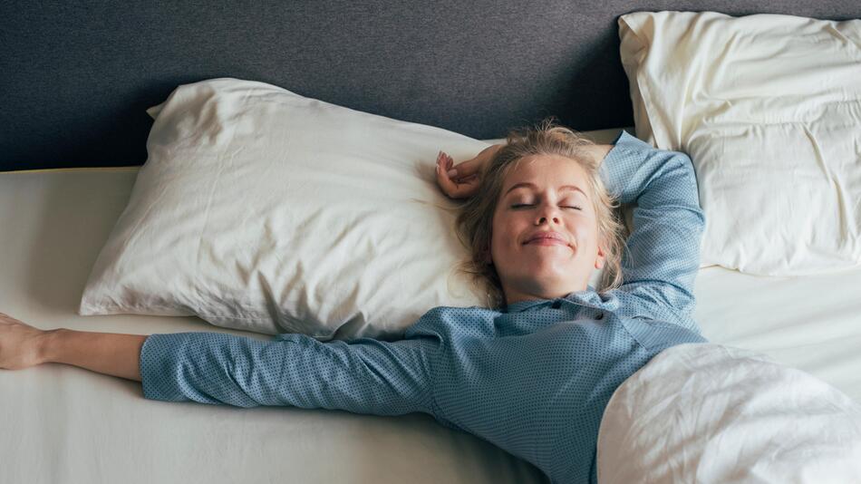 Frau liegt lächelnd im Bett