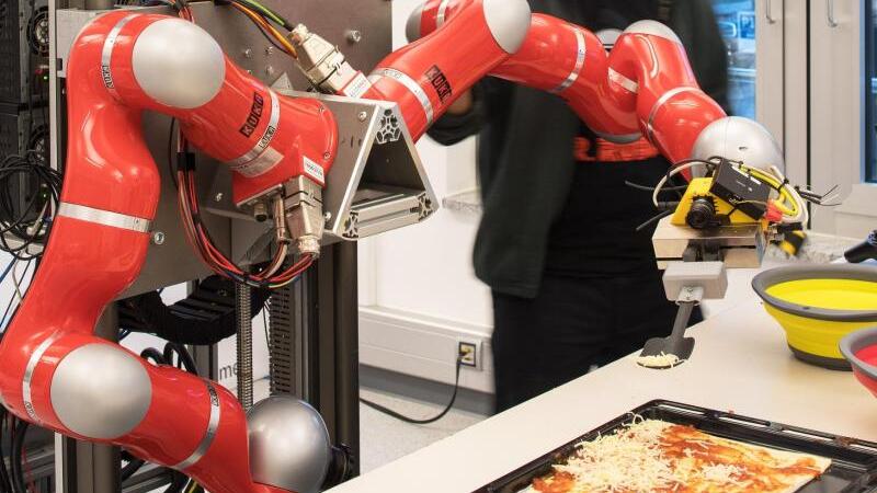 Roboter verteilt Käse auf einer Pizza