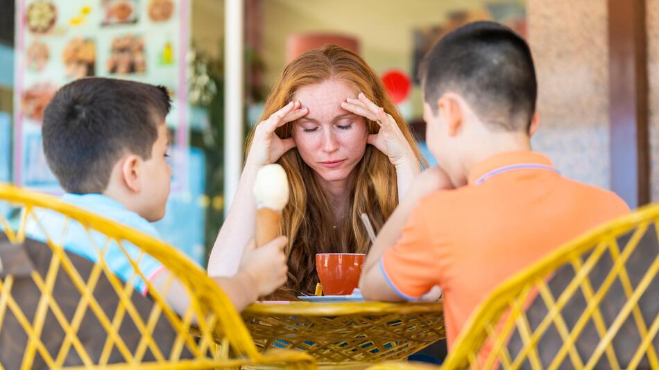 Gestresste Mutter isst mit ihren Kindern Eis