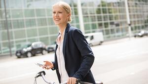 Junge Frau im Business-Casual-Look steht vor einem Büro