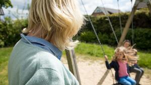 Eine Frau beobachtet Kinder beim Schaukeln