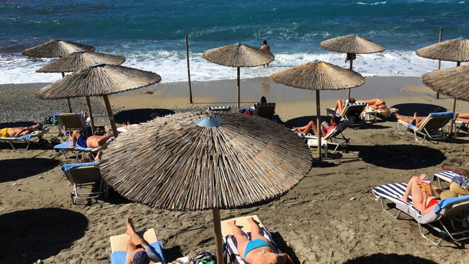 Strand mit Sandstrand mit mehreren sich sonnenden Personen