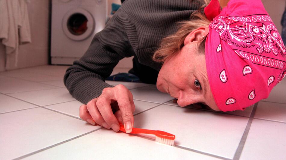 Eine Frau putzt den Boden mit einer Zahnbürste