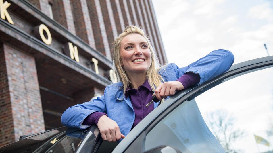 Frau lehnt zufrieden an einem Auto