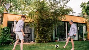 Zwei Männer spielen Fussball im Garten eines Hauses