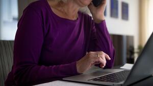 Eine Frau sitzt zu Hause an einem Esstisch am Laptop