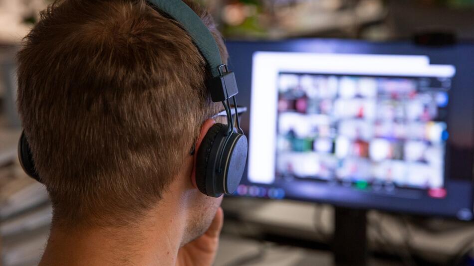 Ein Mann nimmt an einer Videokonferenz teil und trägt Kopfhörer