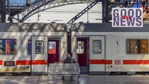 Bahnhof: Ein Mann sitzt auf einer Bank vor einem Zug der Deutschen Bahn mit geöffneten Türen