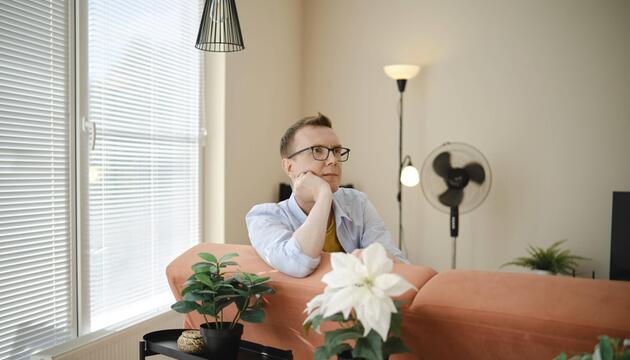 Ein Mann sitzt nachdenklich auf einer Couch.