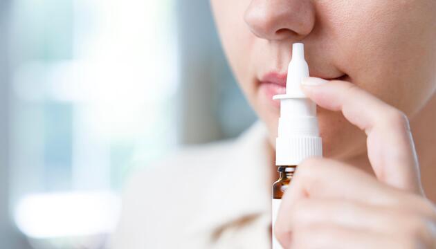 Frau setzt sich einen Pumpspender an die Nase