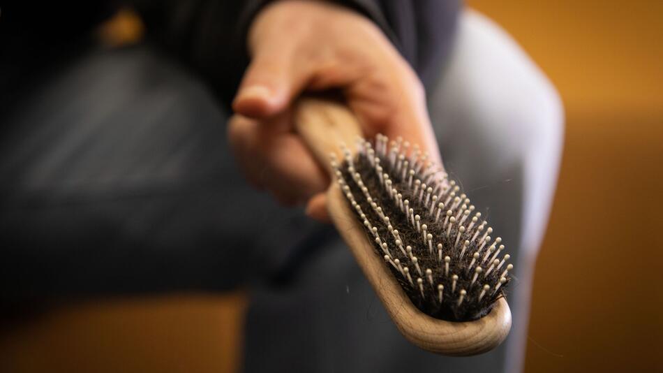 Eine Frau hält eine Haarbürste in der Hand