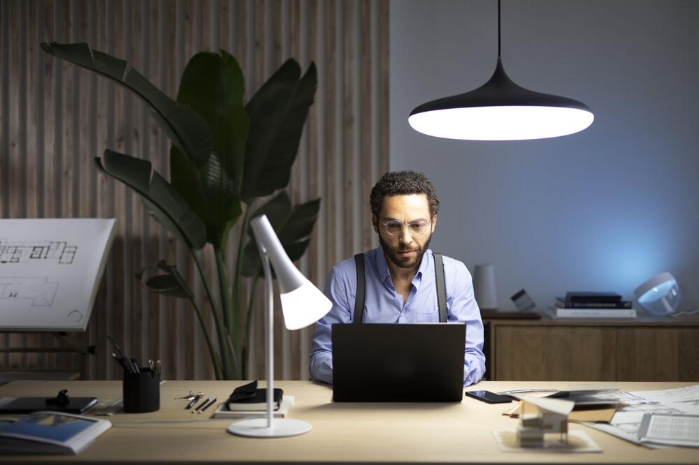 Ein Mann sitzt unter einer Pendelleuchte am Laptop