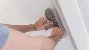 Mann schliesst eine Wohnungstür ab