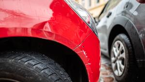 Ein rotes Auto steht mit einem Blechschaden in einer Parklücke