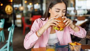 Junge Frau beisst genüsslich in einen Burger