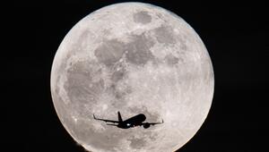 Ein Passagierflugzeug fliegt am Vollmond vorbei