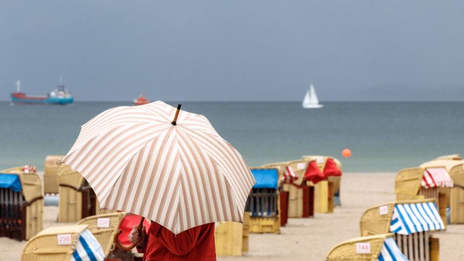 Eine Frau mit Schirm am Strand