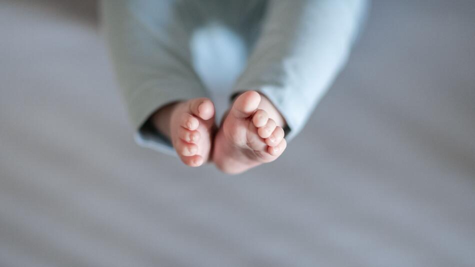 Füsse eines Babys sind in einem Kinderbett zu sehen