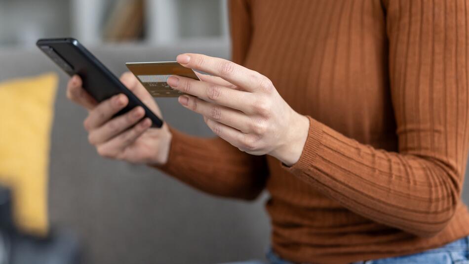 Frau mit Smartphone und Kreditkarte in den Händen