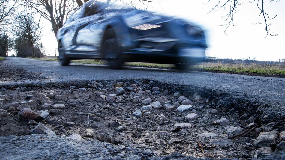 Auto fährt an einem Schlagloch vorbei