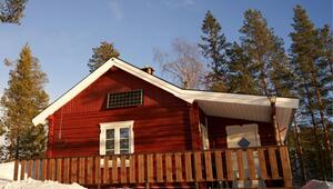 Rotes Holzhaus mit weissem Fensterrahmen und Tür, Solarzelle an der Hauswand, umgeben von ...