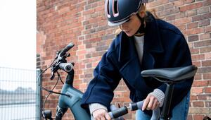 Eine junge Frau schliesst ein E-Bike mit einem Fahrradschloss ab