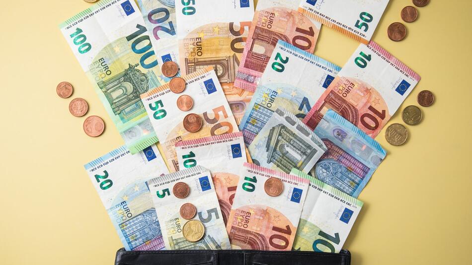 Geldscheine und Münzen fliegen aus einer Geldbörse