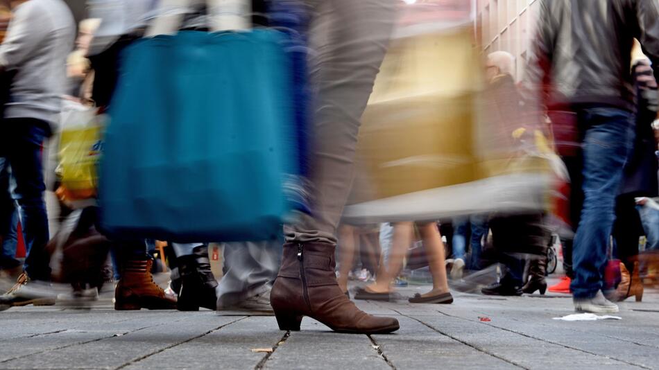 Eine Passantin trägt ihre Einkäufe in Taschen
