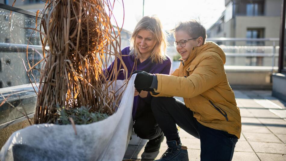 Mutter und Sohn bereiten Balkonpflanzen für den Winter vor