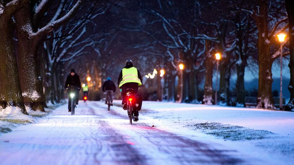 Radfahrer fahren durch eine verschneite Allee